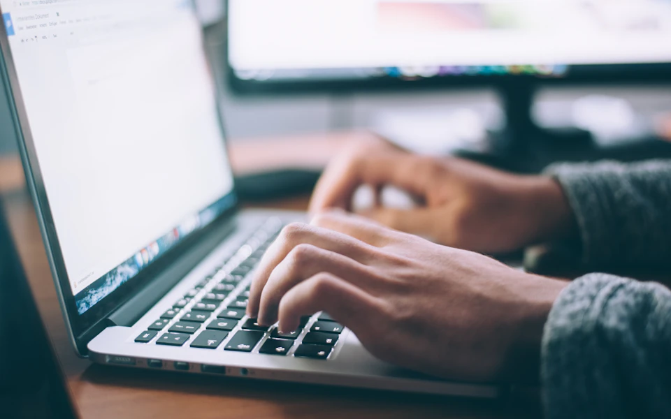 Hands typing on a laptop